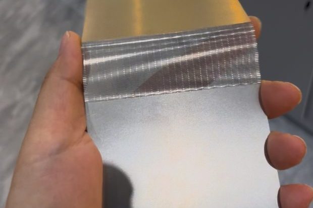 Handheld thin etched metal folding sample showing a dense precision flexible zone