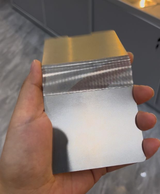 Handheld thin etched metal folding sample showing a dense precision flexible zone