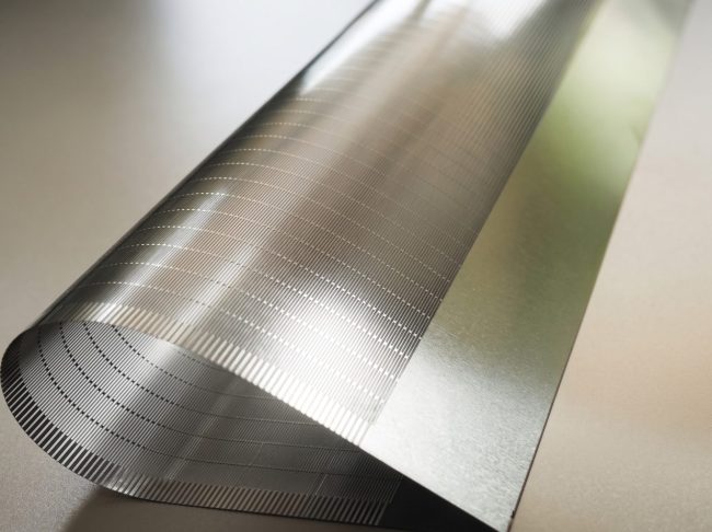 Close-up of fine etched micro-slots in a thin titanium support plate for foldable electronics